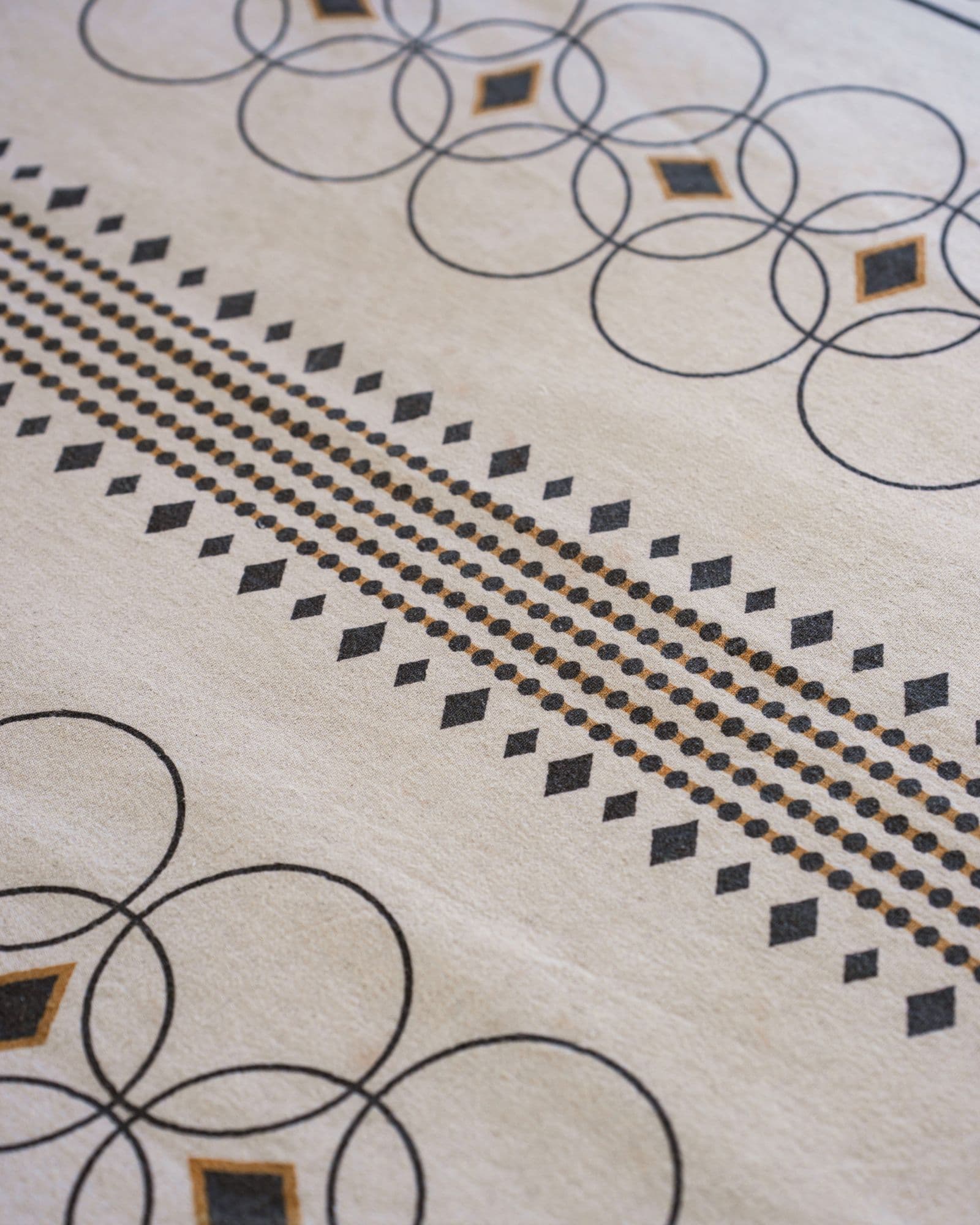 Natural KIND textile with black circle motifs and a geometric border
