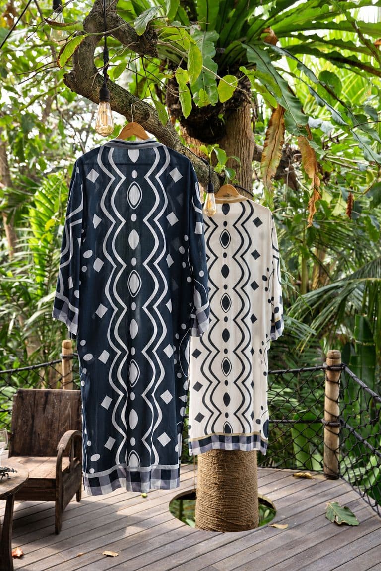 Navy and cream printed KIND kimonos hanging from a tree on a garden deck