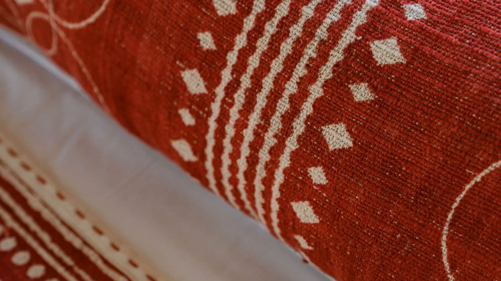 Close-up of a terracotta KIND textile with cream circles, dotted arcs and a geometric border