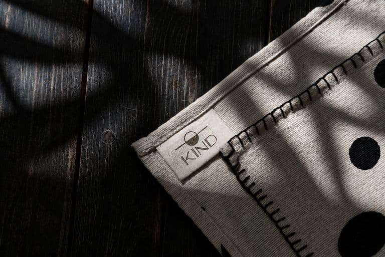 Hand-stitched edge and KIND label on a natural textile